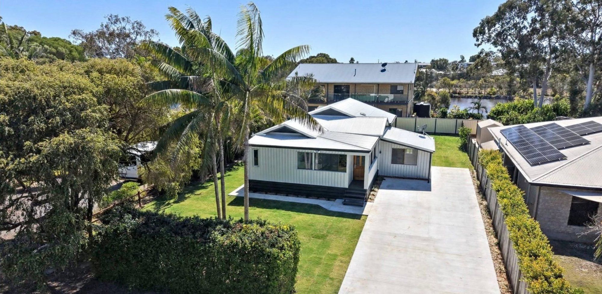 Aerial view of a long new concrete driveway and front path at a Woodgate home, framed by palm trees